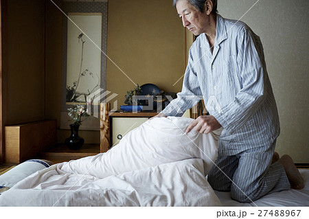 一人暮らしをする高齢者　寝具を畳む男性 27488967