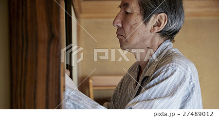 一人暮らしをする高齢者　寝具を畳む男性 27489012