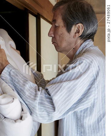 一人暮らしをする高齢者　寝具を畳む男性 27489061