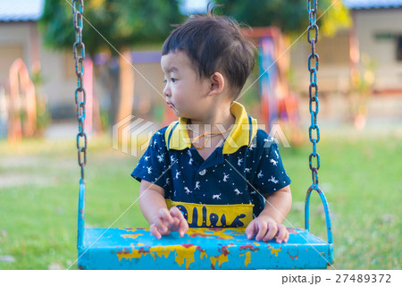 Young Asian boy play a iron swinging at playground Young Asian boy play a iron swinging at playground 27489372