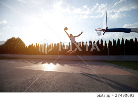Young man jumping and making a fantastic slam dunk Young man jumping and making a fantastic slam dunk 27490692