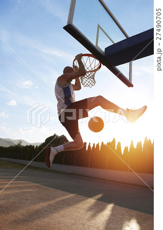 Young man jumping and making a fantastic slam dunk 27490705