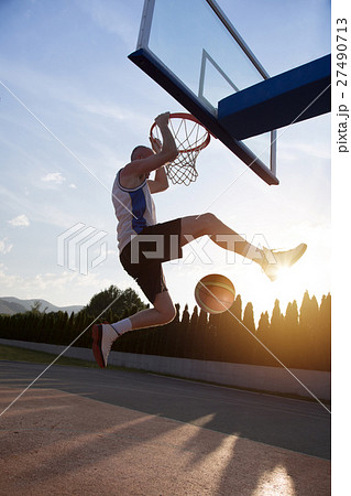 Young man jumping and making a fantastic slam dunk 27490713