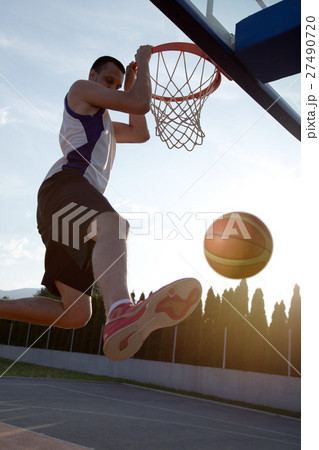 Young man jumping and making a fantastic slam dunk 27490720