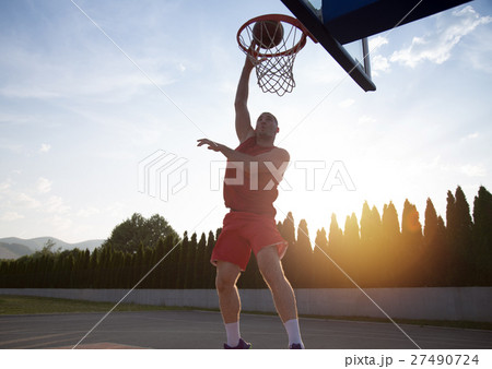 Young man jumping and making a fantastic slam dunk 27490724