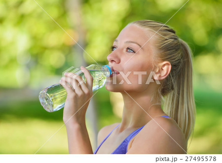 Pretty female runner resting and drinking water 27495578