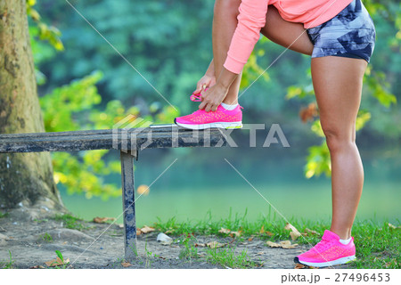Runner girl tying laces shoes at the bench Runner girl tying laces shoes at the bench 27496453