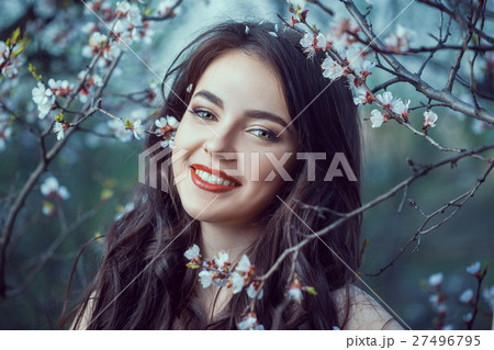 Beautiful girl standing at blossoming tree in the Beautiful girl standing at blossoming tree in the 27496795