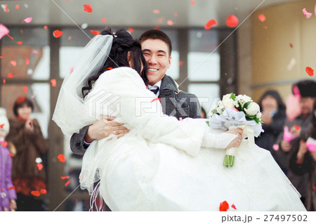 The groom carrying bride in his arms, the crowd 27497502