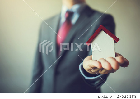 Business man in suit having miniature house Business man in suit having miniature house 27525188