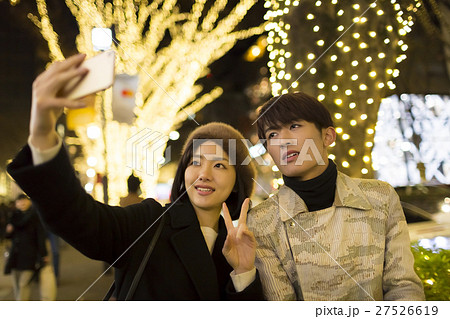 カップル 恋人 東京観光 デート 表参道 クリスマスイルミネーション スマホで記念撮影の写真素材