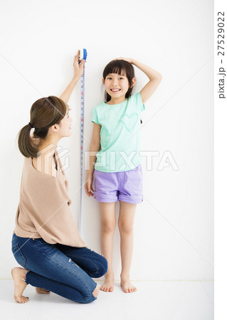 mother measures the growth of her  daughter mother measures the growth of her  daughter 27529022