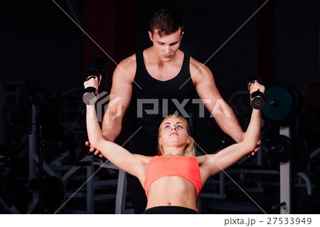 Fitness instructor exercising with his client at 27533949
