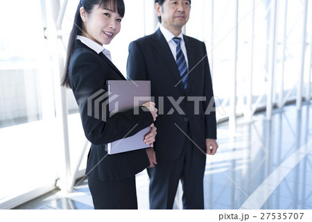 ロビーで笑顔のビジネスウーマンとビジネスマン ロビーで笑顔のビジネスウーマンとビジネスマン 27535707