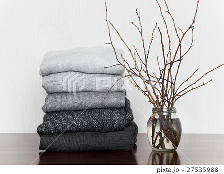 Pile of grey knitted sweaters on wooden table Pile of grey knitted sweaters on wooden table 27535988