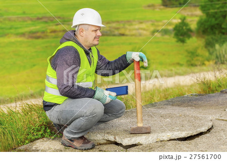 Worker with sledgehammer and tablet PC near broken 27561700