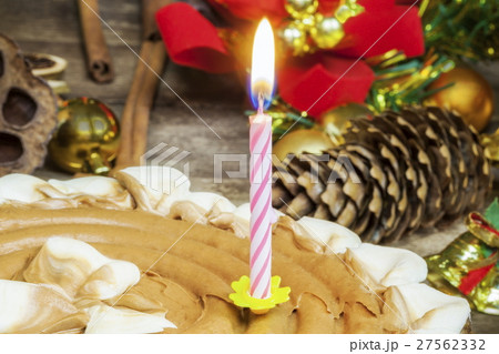 Burning candle in chocolate cake near Christmas de 27562332