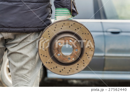 Man holding old brake disc near car  27562440