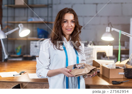 Portrait of young female tailor holding a present 27562954