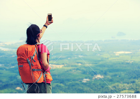 hiker taking photo with smartphone mountain peak 27573688