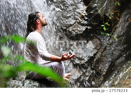 Man sitting in meditation yoga on rock at 27576233