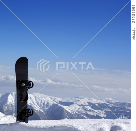 Snowboard in snow near off-piste slope in sun day 27583693