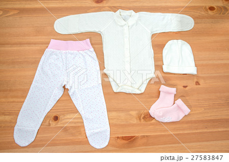 Clothes for newborn girl on a wooden background 27583847