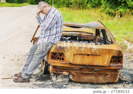 Stressful man on burned down car wreck on the side 27589232