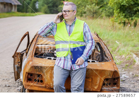 Inspector talking on smart phone near burned down Inspector talking on smart phone near burned down 27589657