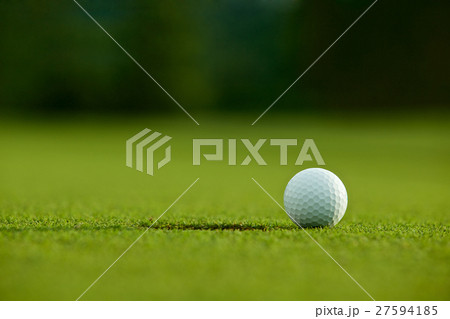 selective focus. white golf ball near hole on gree 27594185