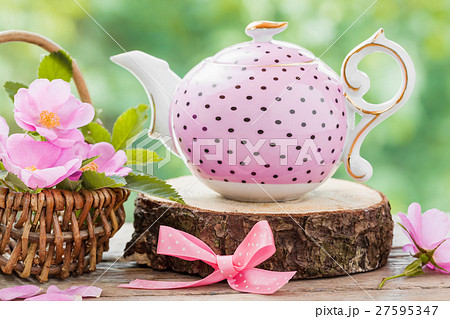 Tea kettle and basket with pink wild roses. Tea kettle and basket with pink wild roses. 27595347
