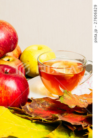 Apples and maple leaves on table next to a cup tea Apples and maple leaves on table next to a cup tea 27606829