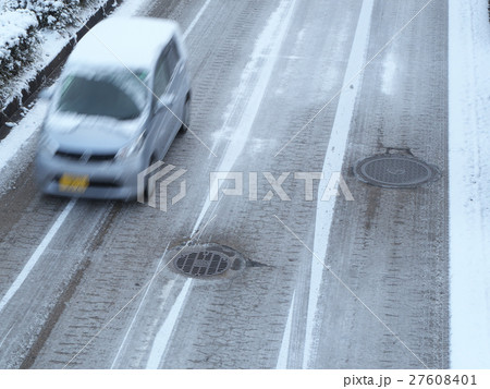 雪道を走行する乗用車とマンホール 27608401
