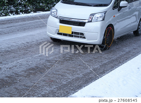 チェーンを装着し 雪道を走行する軽自動車の写真素材