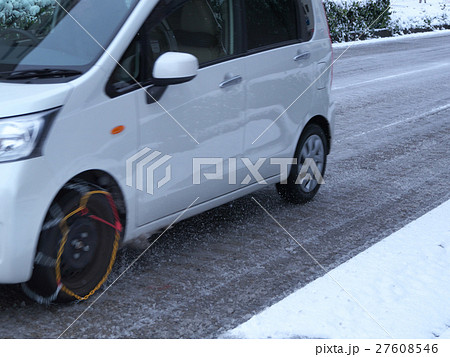 チェーンを装着し 雪道を走行する軽自動車の写真素材