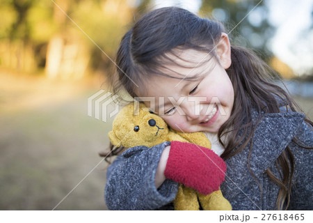 熊のぬいぐるみをもらって喜ぶ女の子の写真素材