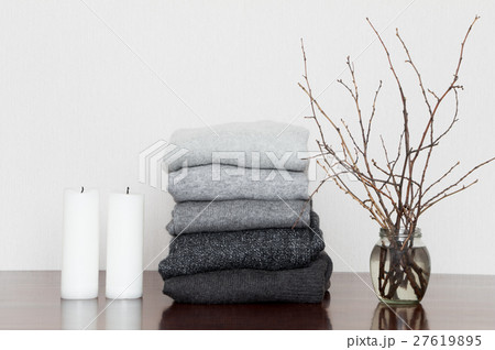 Pile of grey sweaters with candles and branches Pile of grey sweaters with candles and branches 27619895