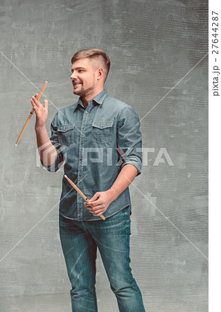 Man holding two drumsticks over gray background Man holding two drumsticks over gray background 27644287