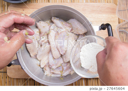 Chef putting flour to chicken wings for cooking Chef putting flour to chicken wings for cooking 27645604