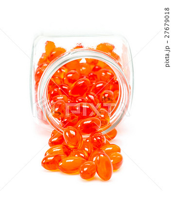Red supplement capsules spill out from bottle 27679018