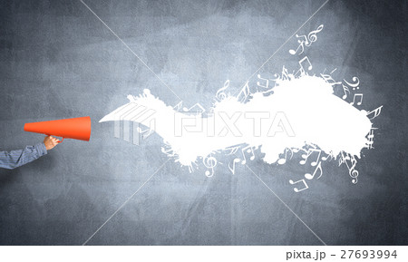 Hand of man holding orange paper trumpet against concrete background Hand of man holding orange paper trumpet against concrete background 27693994