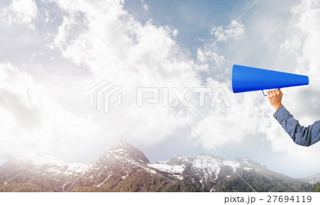 Hand of man holding paper trumpet against natural landscape background 27694119