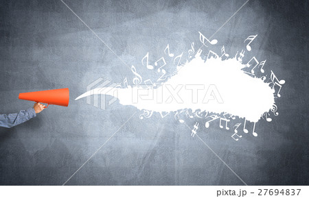 Hand of man holding orange paper trumpet against concrete background 27694837
