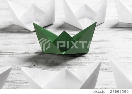 Business leadership concept with white and color paper boats on wooden table Business leadership concept with white and color paper boats on wooden table 27695596