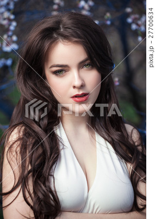 Beautiful girl standing at blossoming tree in the 27700634