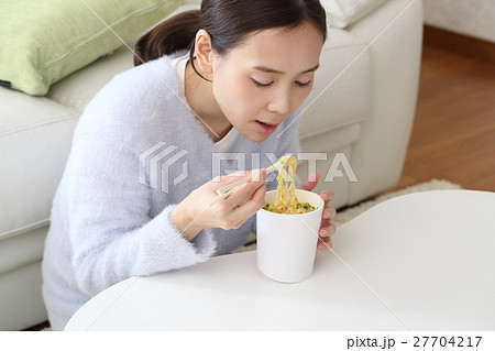 カップラーメンを食べる女性の写真素材