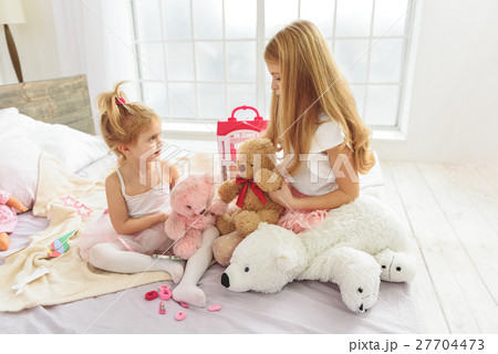 Cheerful sisters having fun with toys Cheerful sisters having fun with toys 27704473