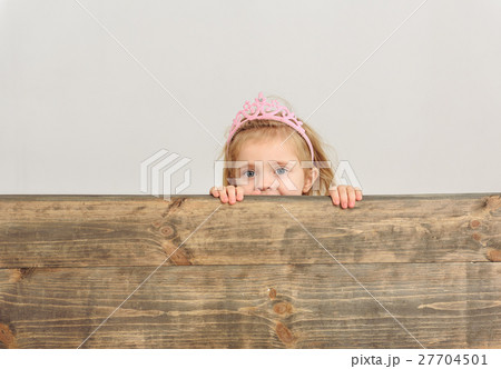 Cute girl peeping over wooden border Cute girl peeping over wooden border 27704501
