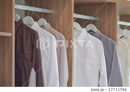 Classic color shirts hanging in wooden wardrobe Classic color shirts hanging in wooden wardrobe 27711766
