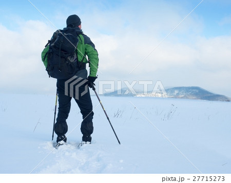 Man with snowshoes take a rest in snow. Man with snowshoes take a rest in snow. 27715273